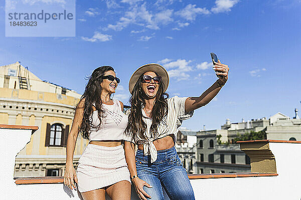 Fröhliche Frau macht ein Selfie mit einer Freundin per Smartphone