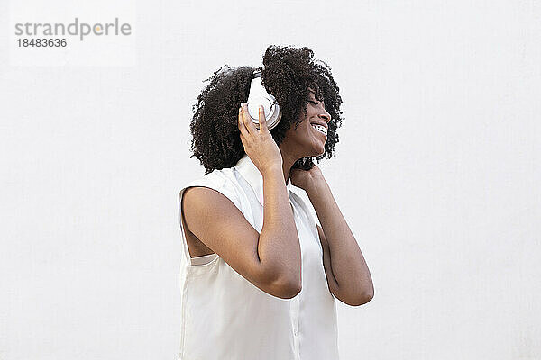 Eine glückliche Frau mit Kopfhörern hört gerne Musik vor weißem Hintergrund