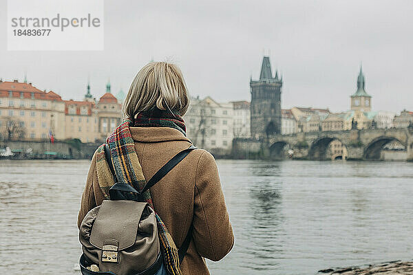 Frau mit Rucksack steht am Fluss