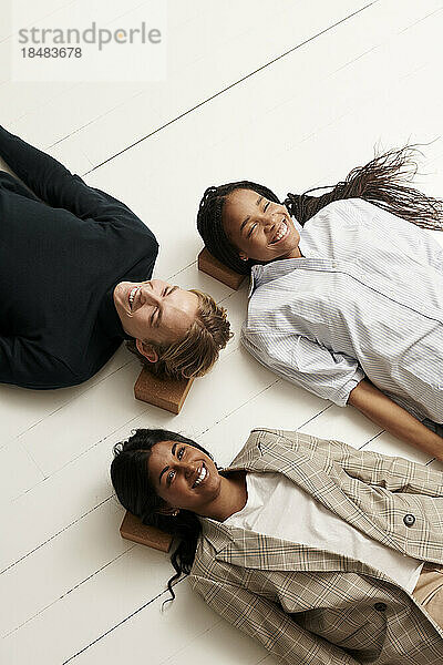 Smiling business colleagues lying on yoga blocks