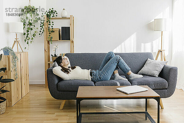 Woman lying down on sofa in living room