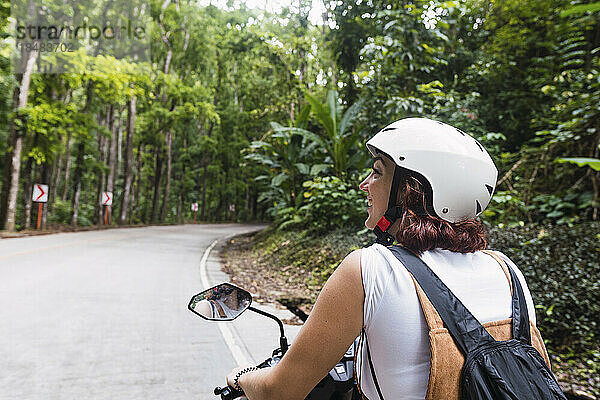 Glückliche junge Frau mit Helm auf dem Motorrad