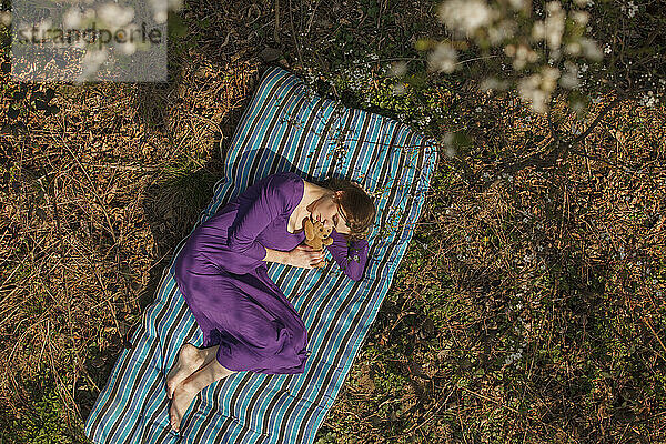 Junge Frau mit Stoffspielzeug entspannt sich auf der Matratze