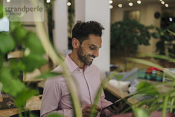 Smiling mature businessman using tablet PC in office