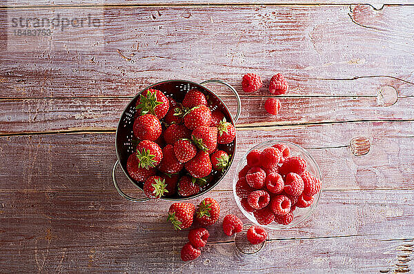 Studio shot of bowls with fresh strawberries and raspberries