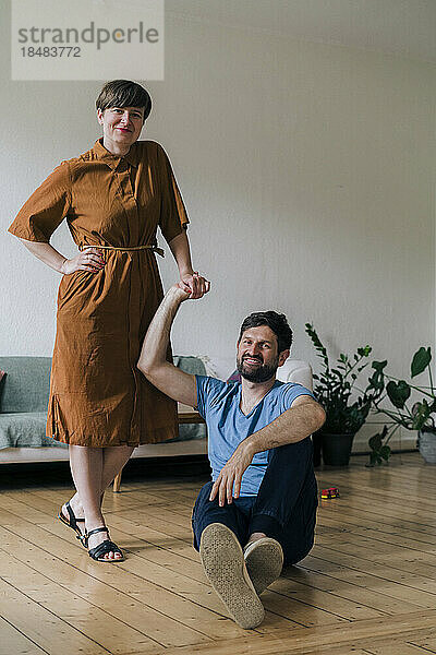 Woman with hand on hip standing by man at home