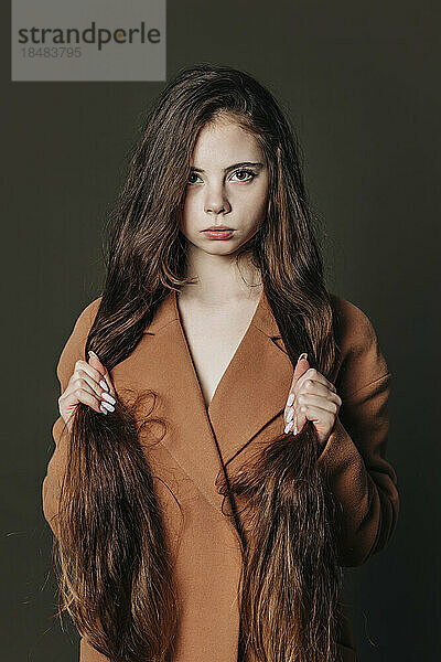 Teenage girl with long hair against gray background