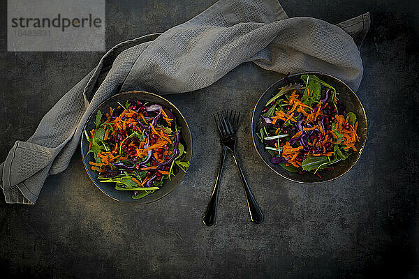 Studioaufnahme von zwei Tellern mit verzehrfertigem veganem Salat vor schwarzem Hintergrund