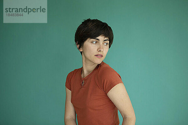 Young woman with short hair against green background