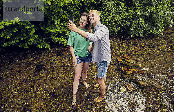 Junges Paar macht Selfie mit Smartphone  das im Strom steht