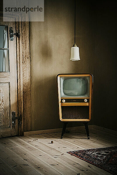Alter Fernseher und Pendelleuchte im leeren Raum