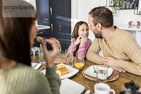 Happy girl with father having breakfast at dining table