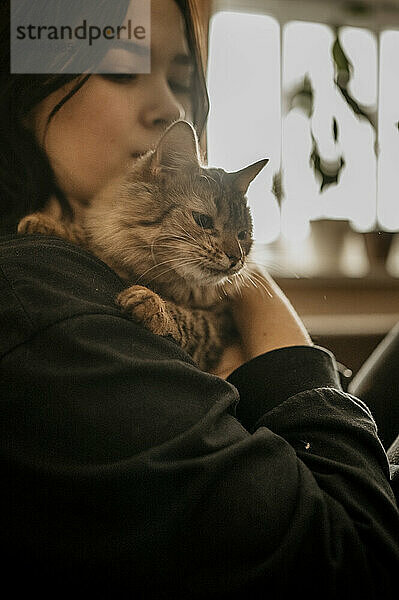 Teenage girl holding cat in arms