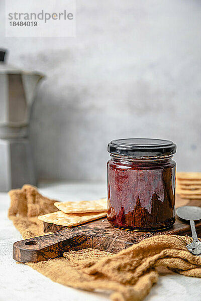 Homemade strawberry jam in jar with crackers