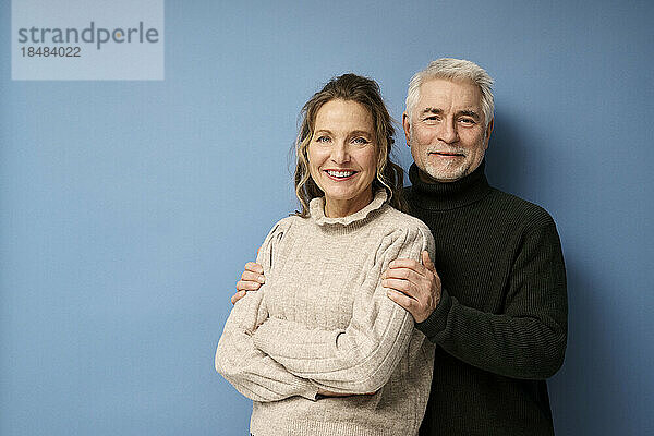 Glückliches älteres Paar  das vor blauem Hintergrund zusammensteht