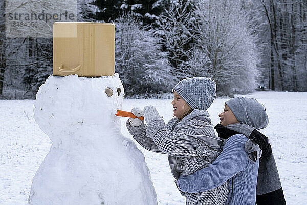 Bruder und Schwester bauen Schneemann