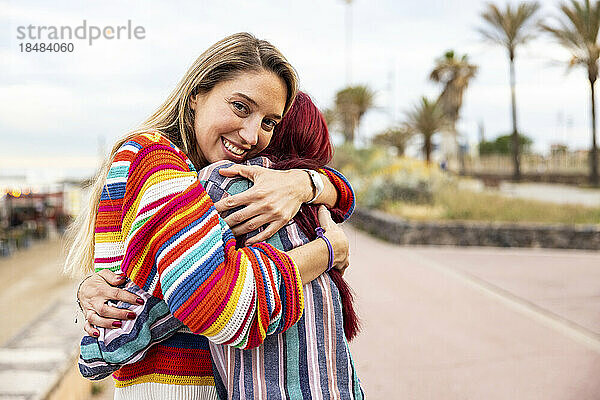 Glückliche Frau umarmt Freund an der Promenade