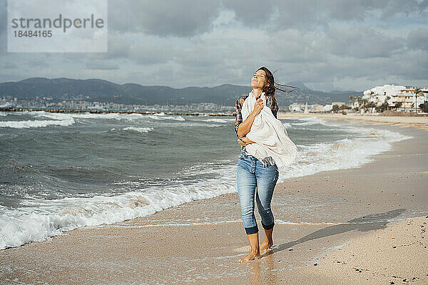 Frau spaziert am Strand am Meeresufer entlang