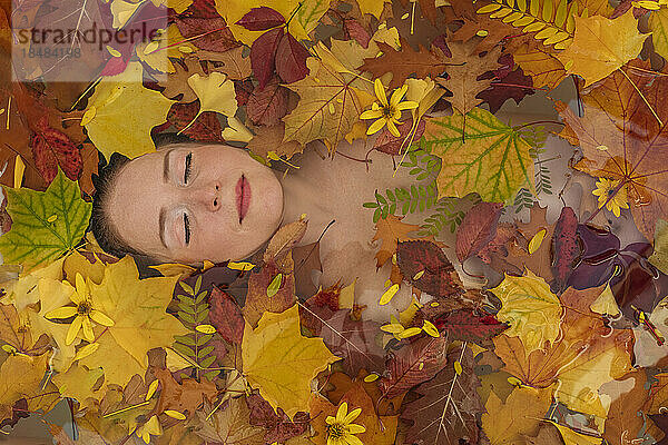 Frau entspannt sich mit Herbstblättern im Wasser