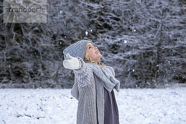 Lächelndes süßes Mädchen  das den Schnee im Winter genießt