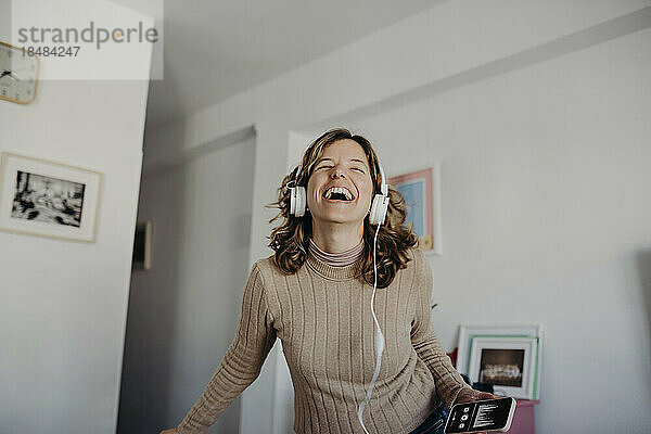 Glückliche Frau mit Kopfhörern  die zu Hause Musik hört