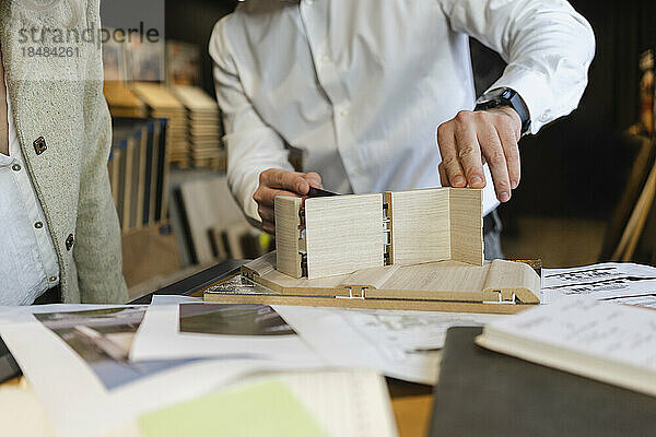 Nahaufnahme eines Mannes  der im Architekturbüro an einem Holzmodell arbeitet