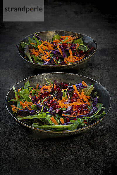 Studioaufnahme von zwei Tellern mit verzehrfertigem veganem Salat vor schwarzem Hintergrund