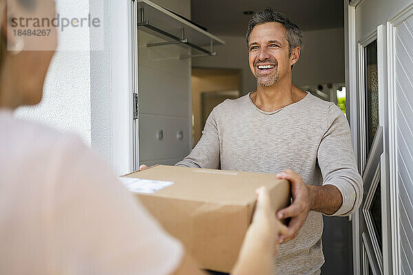 Happy man receiving parcel at the front door