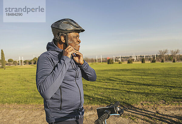 Nachdenklicher älterer Mann mit Helm an sonnigem Tag