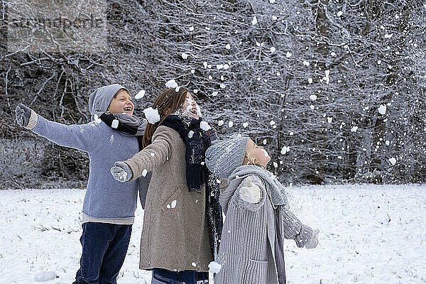 Fröhliche Brüder und Schwestern in warmer Kleidung genießen den Schnee