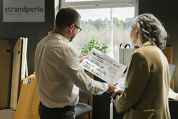 Two colleagues working on construction plan in architect's office