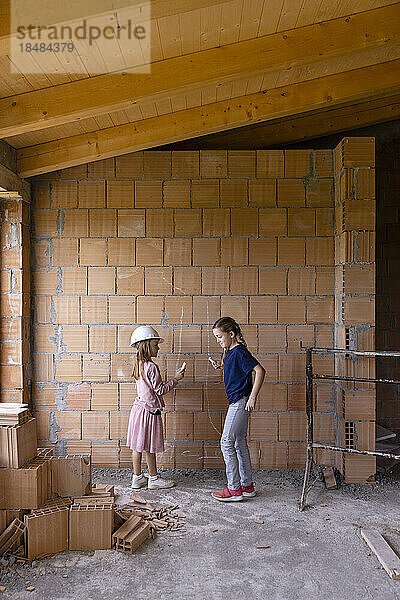 Girls with chalk drawing on brick wall at construction site