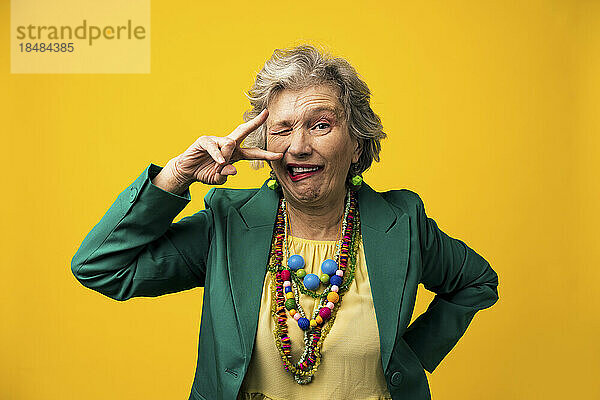 Senior woman with facial expressions against yellow background