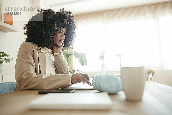 Junge Geschäftsfrau mit Afro-Frisur benutzt Laptop im Büro