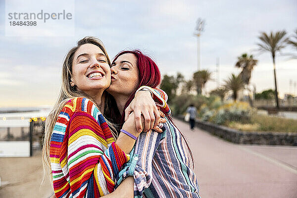 Glückliche Frau küsst Freundin an der Promenade auf die Wange