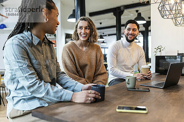 Lächelnde Geschäftsleute sitzen mit einer Tasse in der Bürokantine