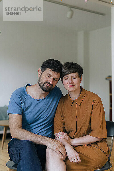 Mature couple with eyes closed sitting at home