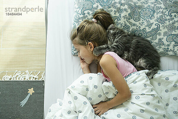 Sleeping girl with cat on bed at home