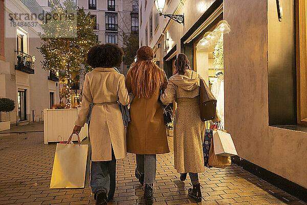 Junge Frau mit Freunden beim Einkaufen und Spazierengehen auf dem Fußweg