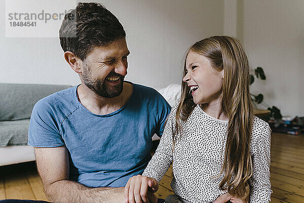 Girl enjoying with father sitting in living room