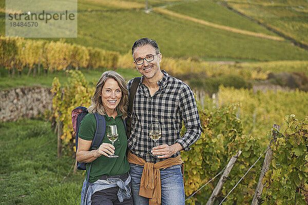 Fröhliche Touristen mit Weingläsern stehen im Weinberg