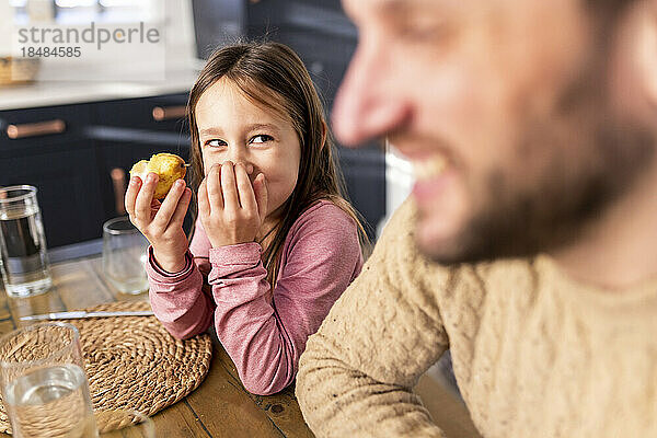 Glückliches Mädchen beim Frühstück mit Vater am Tisch sitzend