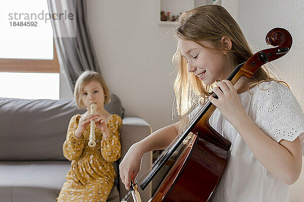 Happy girls playing musical instruments at home