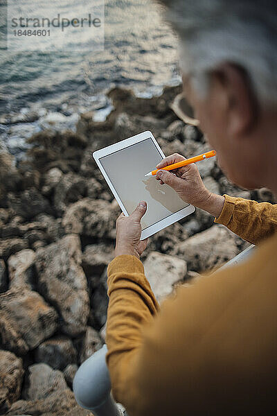 Älterer Mann benutzt Tablet-PC mit digitalisiertem Stift