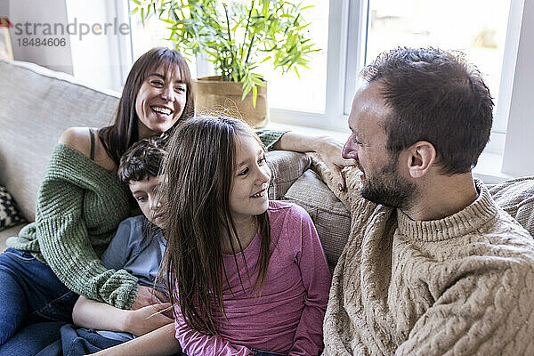 Happy woman sitting with family on sofa at home