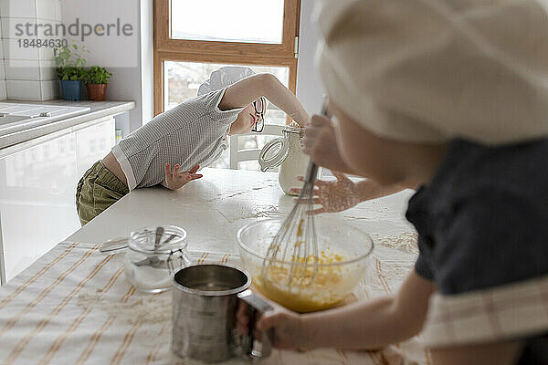 Junge nimmt Mehl  um zu Hause Teig zuzubereiten