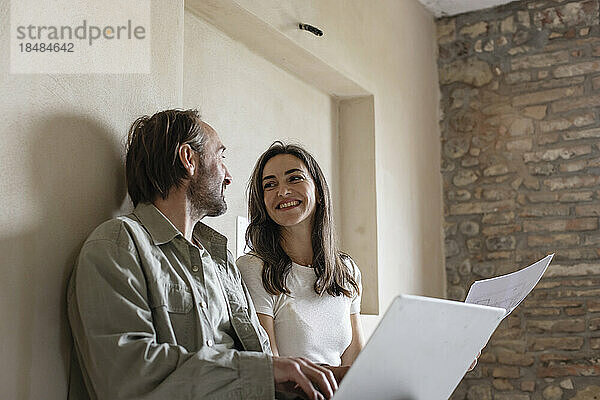 Glückliche Frau und Mann sitzen mit Laptop zu Hause