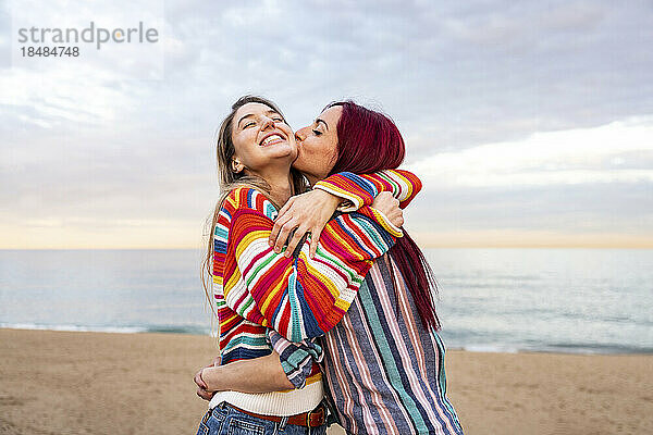 Rothaarige Frau küsst Freundin am Strand
