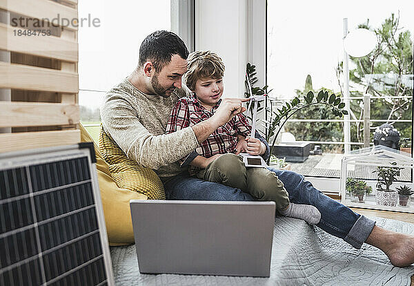 Vater spricht mit Sohn  der zu Hause ein Windturbinenmodell in der Hand hält