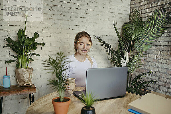 Lächelnde Geschäftsfrau  die im Büro am Laptop arbeitet